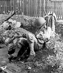 ENLISTED MAN CATCHES UP ON LOST SLEEP after spending all night
packing and moving with his regiment to the port of embarkation in preparation
for a move from New Caledonia to another South Pacific island. The hilt of the
saber which shows on the right side of the pack is that of an Australian cavalry
saber issued in lieu of a machete.