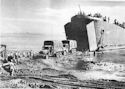 COAST GUARD-MANNED LST-68 DROPS ITS RAMP AT THE END OF AN IMPROVISED WHARF