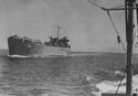 A COAST GUARD-MANNED LST (LANDING SHIP, TANK) THRUSTS ITS SNUB NOSE THROUGH A CALM SEA