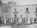 MEMBERS OF THE AFRIKA KORPS OF THE GERMAN ARMY ARE MARCHED ALONG THE SICILIAN WATERFRONT FOR TRANSFER AS PRISONERS OF WAR TO A COAST GUARD-MANNED ASSAULT TRANSPORT OFF SHORE