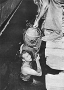 H. C. Zagary, CBM, puts on a diving helmet to inspect the bottom of a PT at a Solomons base