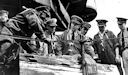 Image: USN NR&L (MOD) 39751 Part of salvage crew discussing salvage of USS California. From left to right are: J. M. Ephland, CSF, Master Diver; LT. W. L. Painter, USNR, Officer in Charge of Work; CDR J. F. Warris, USN, Temporary Commanding Officer; CAPT H. N. Wallin, USN, Salvage Officer; LT G. W. Greely, USNR, Assistant Salvage Officer; LT W. M. Bjork, USNR, Assistant Salvage Officer; and LT J. W. Darroch, USNR, Assistant Salvage Officer.