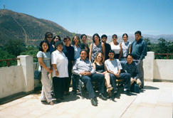 Participants attending a seminar presented by Laura Soto-Barra in Cochabamba pose for a group photo. The setting is at the Universidad Catolica Boliviana's campus on the roof patio. Dean Fernando Andrade, sitting on left, is seated next to Laura. The majestic Andes, the warm sunshine and the blue skies are a constant in Bolivia.
