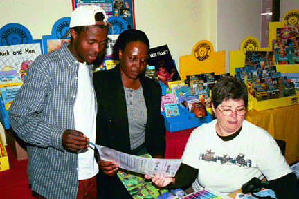 Two community library volunteers choose materials for the library with the help of WLP volunteer Lynn Mitchell.