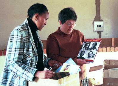 WLP volunteer Lynn Mitchell and Department of Education employee Bussi Ndawo examine books that have been donated by a municipal library.