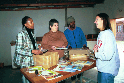 Peace Corp volunteer Carrie Witt goes through a box of donated books with (from right) library committee chairman Herman Mongoale, WLP volunteer Lynn Mitchell and Department of Education employee Bussi Ndawo.