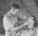 An officer of one of the S.A. Medical Corps' mobile field dental units in the forward areas in Kenya examines an infantryman's teeth.