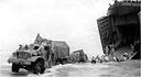 4-TON 6X6 STANDARD TRUCK, with closed cab, towing a 155-mm. howitzer off the ramp of an LST