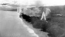 low-flying North American B-25 Mitchell medium bombers leaving Japanese planes and installations burning