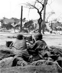 INFANTRYMEN ON THE ALERT in a street of Manila man their .30-caliber Browning machine gun M1919A4