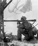 PARATROOPER, armed with a U.S. carbine M1A3 with a folding pantograph stock, fires a bazooka at an enemy pillbox