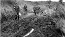 Infantrymen pushing along a muddy, primitive road