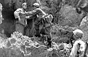 Japanese prisoner being searched at the entrance of a cave after he has surrendered