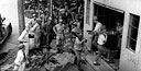MILITARY POLICEMEN STAND GUARD as Japanese soldiers carry rifles, light machine guns, and side arms from trucks into a building used as a collecting point