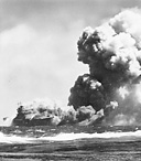 USS WASP lists to starboard, 15 September 1942, as smoke billows from the ship