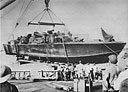 USS Cyrene lifts a PT aboard for major hull repair